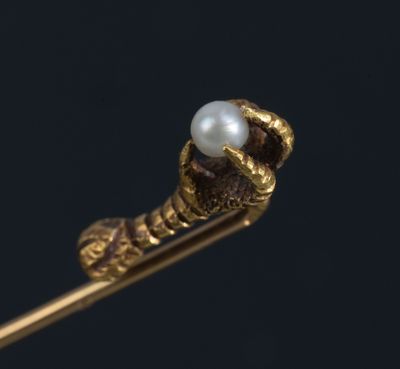un gros plan sur un bijou en or serti d'une perle