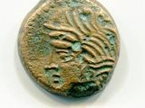 une vieille pièce de monnaie ornée d'un motif, posée sur une surface blanche