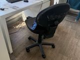 a desk with a computer and a chair in the room