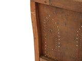 a wooden chair that has a wooden seat with studding on it
