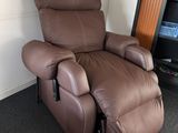 un fauteuil inclinable marron dans une pièce où se trouve une bibliothèque