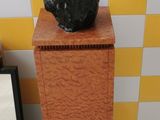 a statue of a dog sitting on top of a wooden pedestal