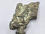 une image représentant une tête de dragon en métal sur un fond blanc
