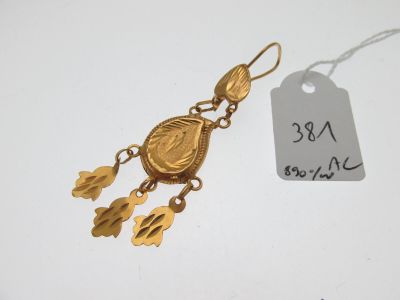 une photo d'une paire de boucles d'oreilles en or avec une étiquette attachée