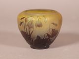 a yellow vase with flowers on it on a white surface