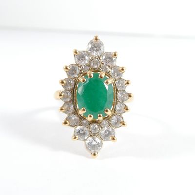 gros plan d'une bague avec une pierre verte entourée de diamants