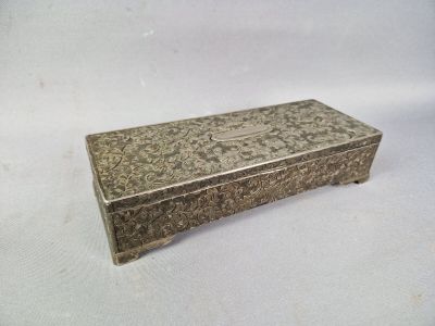 une vieille boîte en argent posée sur une table blanche