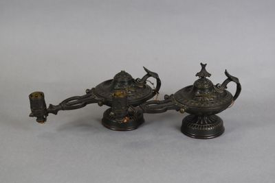 pair of antique brass oil lamps on pedestals on a white background