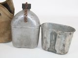 two metal containers and a bag on a white surface