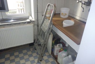 a ladder leaning against the wall in a small kitchen
