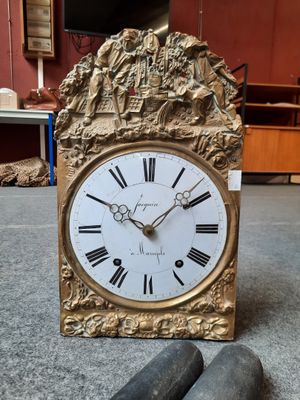 a gold clock with roman numerals on the face