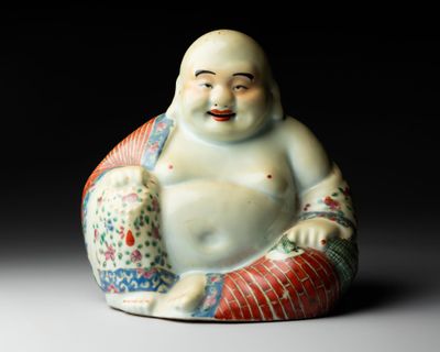 une petite statue représentant un Bouddha souriant, assis sur un coussin