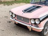 a pink and black car parked in a parking lot