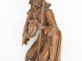 statue en bois représentant un homme muni d'un bâton et portant un chapeau, sur fond blanc