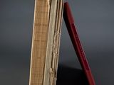 a red pencil sticking out of a stack of old books