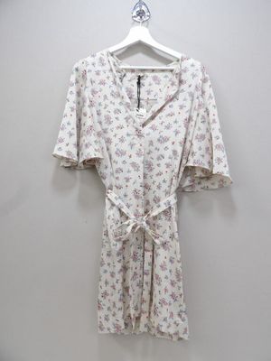 a white shirt with a floral print on it hangs on a hanger