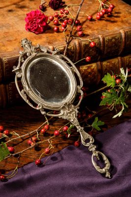 a silver mirror sitting on top of a wooden table