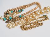 several pearls and gold necklaces on a white surface