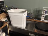 a picture of a kitchen with a sink and a trash can