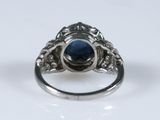 a close up of a ring with a blue stone surrounded by diamonds