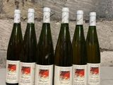 six bottles of wine are lined up in a row against a stone wall