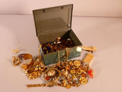 une boîte remplie de bijoux en or posée sur une surface blanche