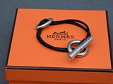 une boîte orange contenant un bracelet argenté et un cordon noir