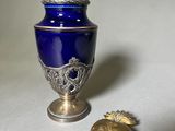 un vase bleu et un cœur doré posés sur une table blanche