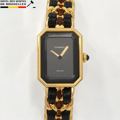 une montre noire et dorée, entourée d'une chaîne