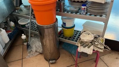 a large orange container sitting on a metal shelf in a kitchen