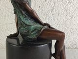 statue of a woman sitting on a stool with her legs crossed