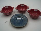 quatre bols rouges et bleus et une assiette posés sur une table blanche