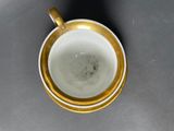 a white cup with a gold rim sitting on a table