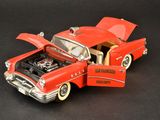 a red toy car with its hood open on a black surface