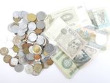 une pile de billets et de pièces posée sur une surface blanche