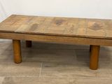 une vieille table basse en bois avec un plateau en carrelage, posée sur un sol carrelé