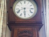 une grande horloge de parquet en bois, placée dans un coin de la pièce