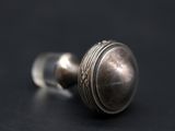 a close up of a silver knob on a black surface