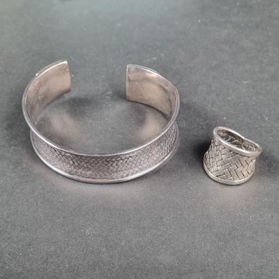 un bracelet et une bague en argent posés sur une table, à côté d'un objet en argent