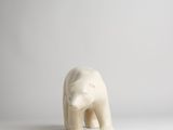 a small white polar bear standing on a white surface