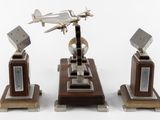 three metal airplanes on a wooden stand on a white surface