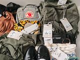 a pile of luggage that includes a backpack, a pair of shoes, a purse, and a pair of shoes