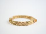 a close up of a gold bracelet on a white surface