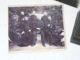 an old photo of a group of men sitting next to each other on a table