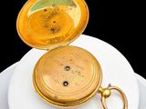 a gold pocket watch sitting on top of a white plate