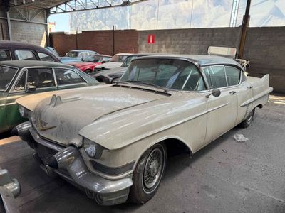 Les voitures sont garées dans un garage où il y a beaucoup de bric-à-brac par terre.