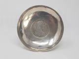 a close up of a silver plate with a coin on it