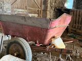 a red wheelbarrow in the middle of a barn filled with dirt