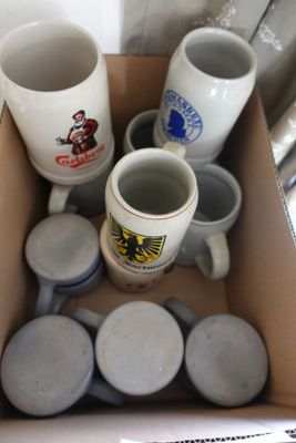 une boîte remplie de tasses à café et de mugs posée par terre