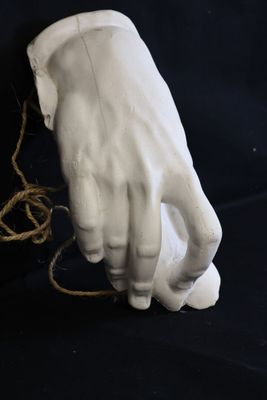 a statue of a hand holding a string on a black background